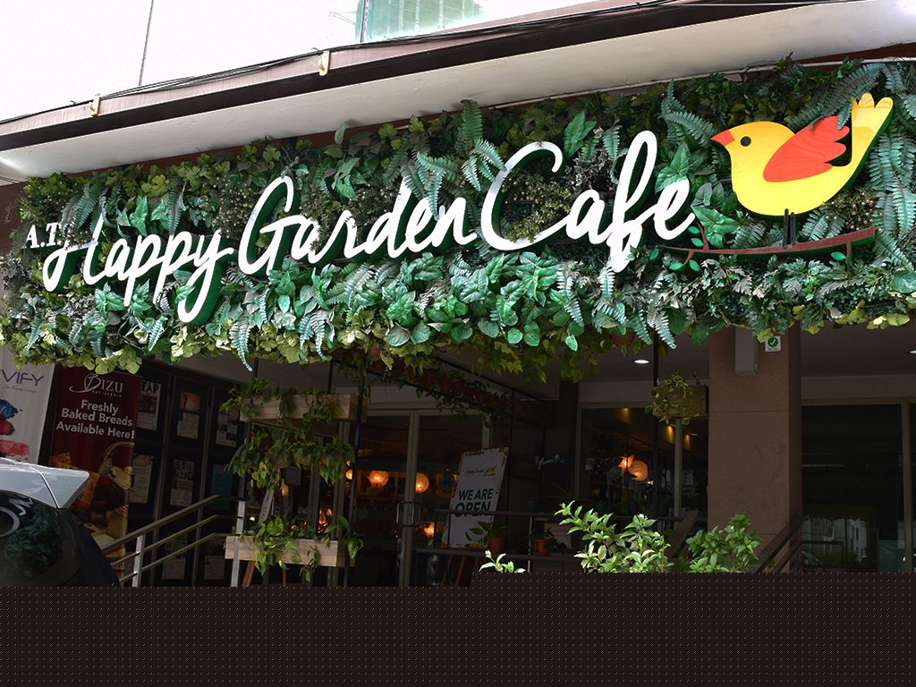 Happy Garden Cafe exterior storefront with green signage and lush plants on Jupiter Street, Makati